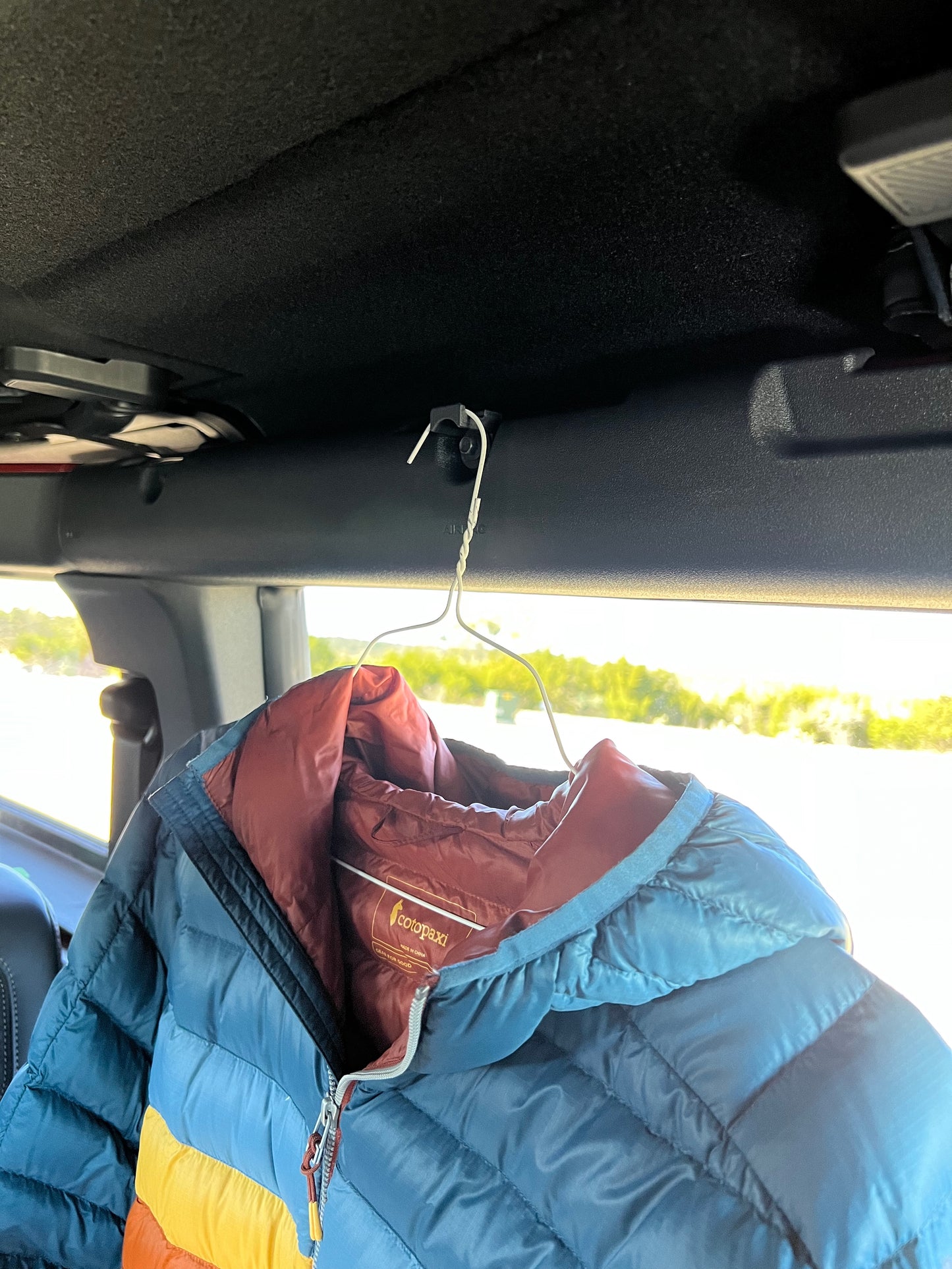 Colorful jacket hanging in Ford Bronco from garment hook